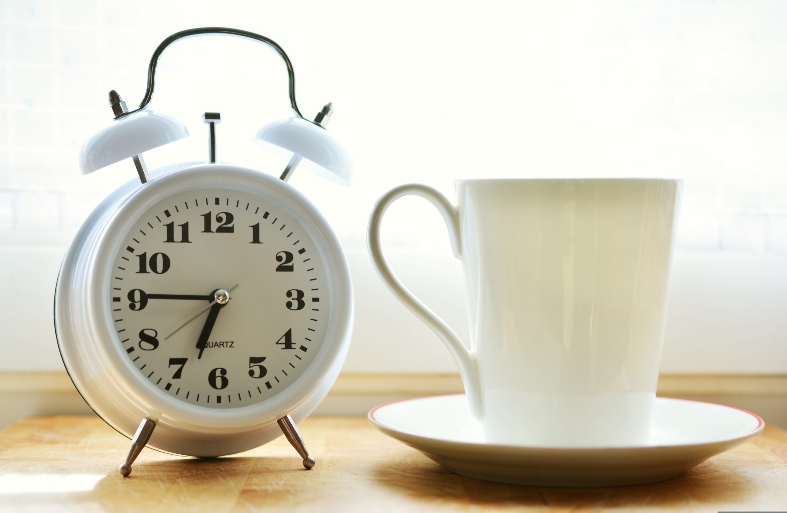 Sveglia accanto a tazzina al mattino presto: il ritorno agli orari di lavoro dopo le ferie mette alla prova l'orologio biologico