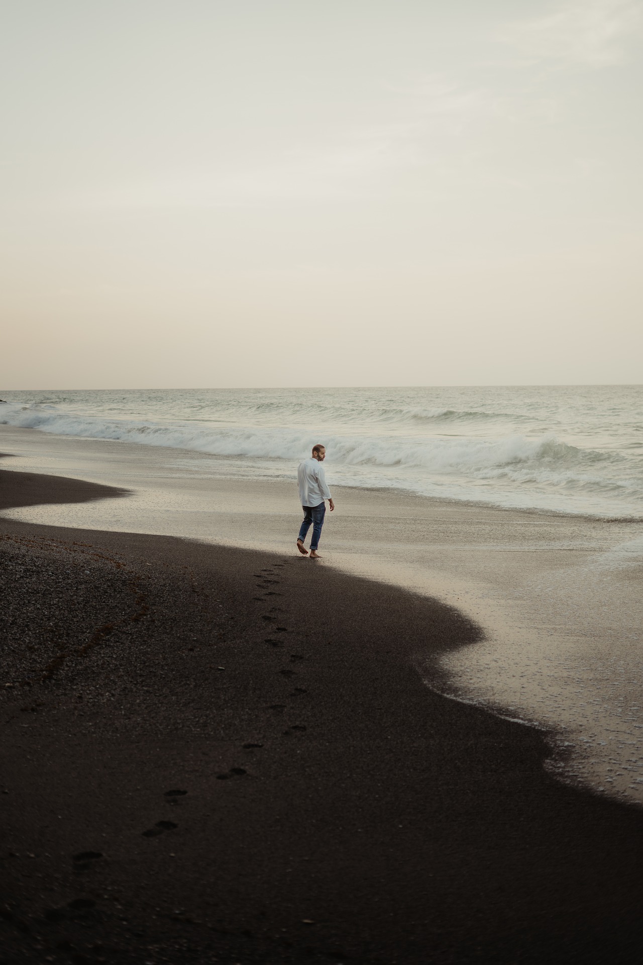 Persona in piedi da sola su una spiaggia guardando il mare: per alcuni le vacanze generano ansia e malessere invece di riposo