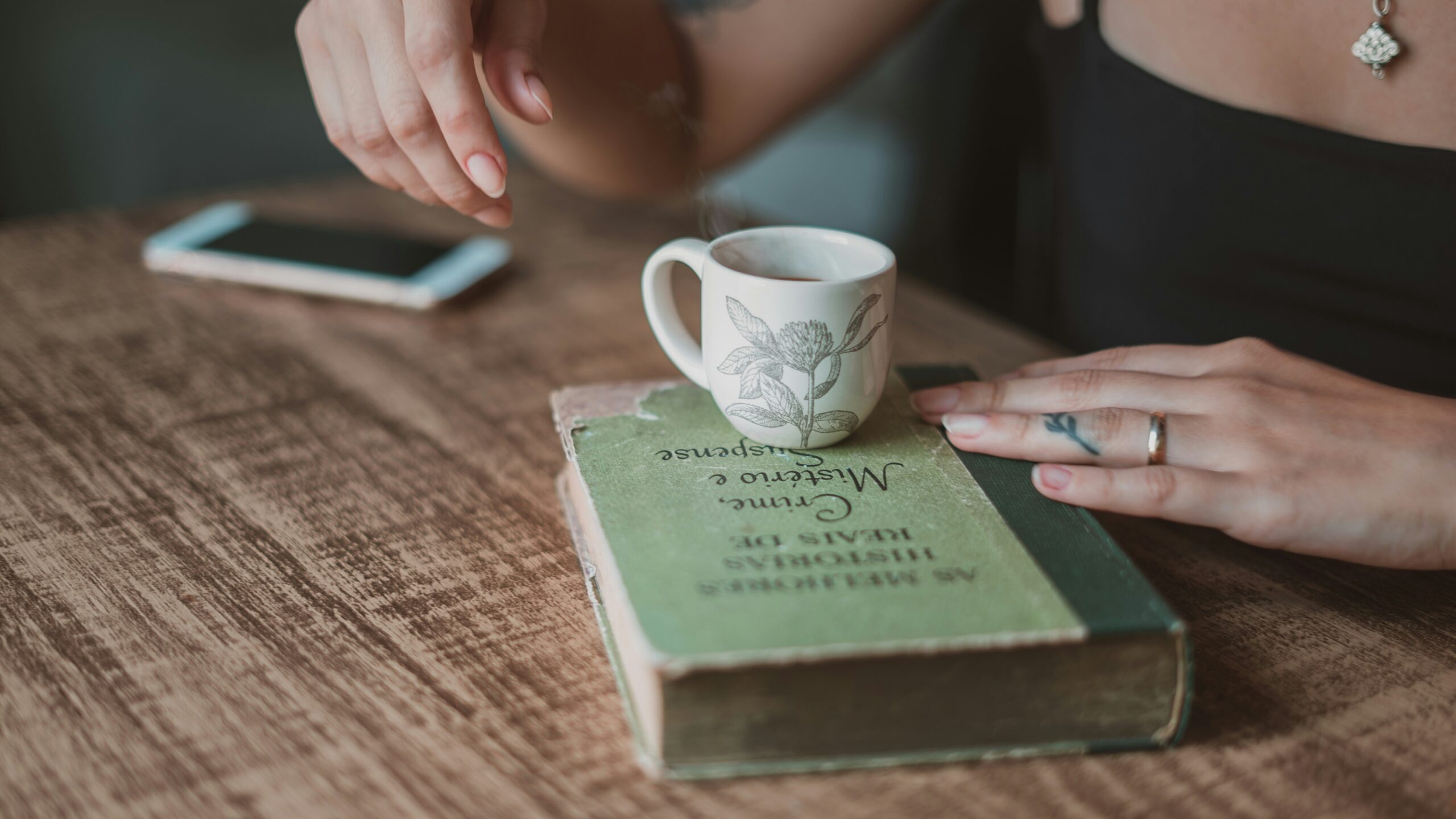 Telefono spento appoggiato su un tavolo accanto a un libro: in vacanza ridurre l'uso dello schermo aiuta a riposare la mente
